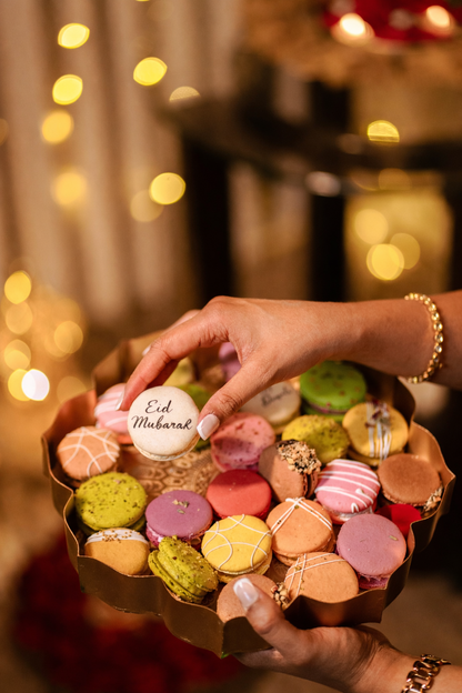 A plate full of colorful macarons and one that says eid mubarak