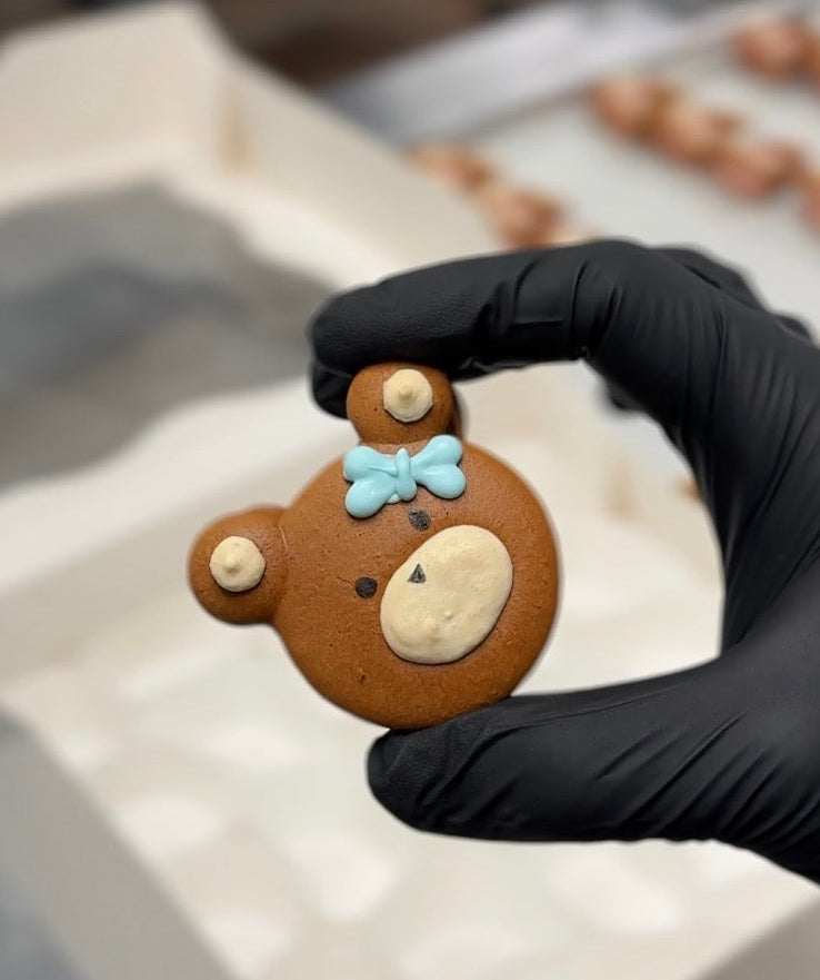 a small bear-shaped macaron with a blue bow tie in a kitchen setting.